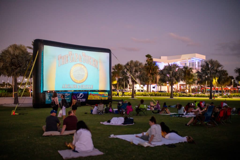 People sit down on blankets as they wait for a free movie to start in a park in Clearwater. 