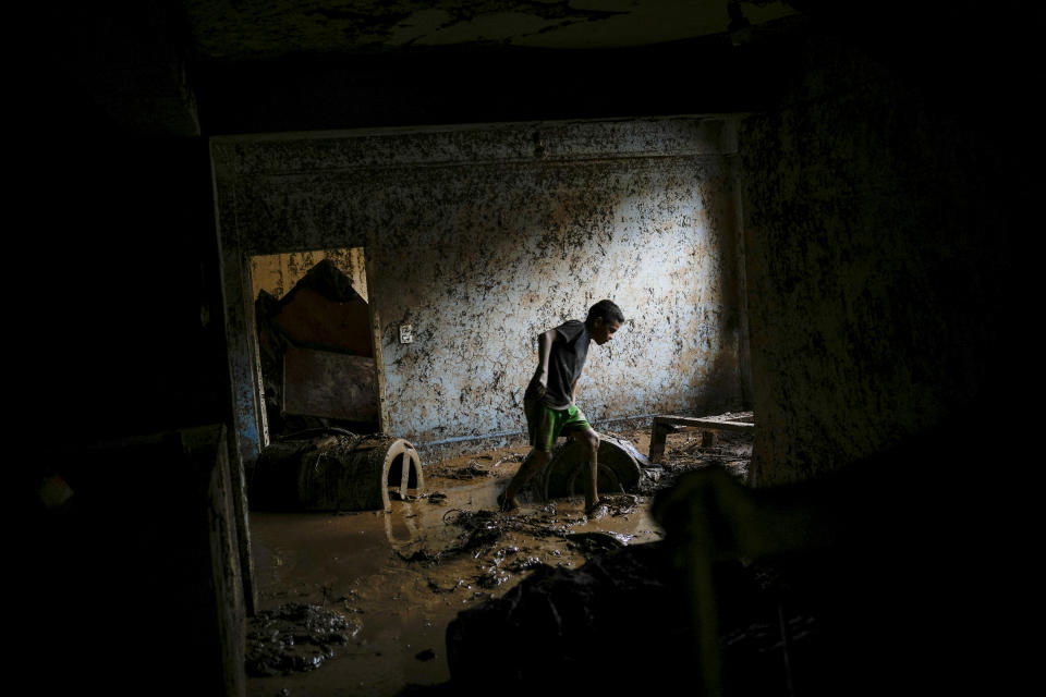Emanuel Sanchez works to remove mud from inside his flooded home in Las Tejerias, Venezuela, Sunday, Oct. 9, 2022. At least 22 people died after intense rain overflowed a ravine causing flash floods, Vice President Delcy Rodríguez said. (AP Photo/Matias Delacroix)