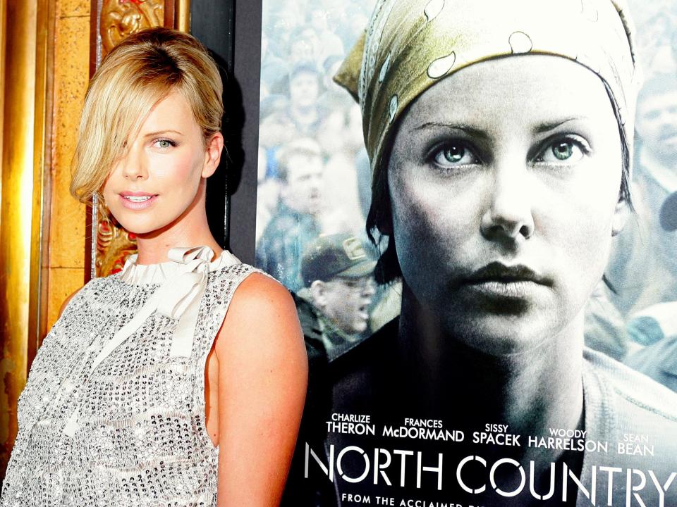 Charlize Theron in front of a poster for the movie "North Country."