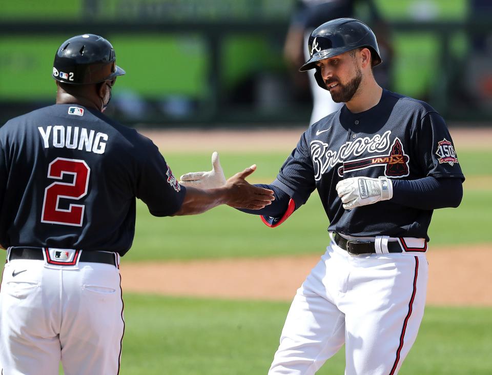 Atlanta Braves Ender Inciarte, right, gets five from first base coach Eric Young, left, after hitting a single against the Minnesota Twins during the third inning of an MLB spring training game Tuesday, March 2, 2021, in North Port, Fla. (Curtis Compton/Atlanta Journal-Constitution via AP)