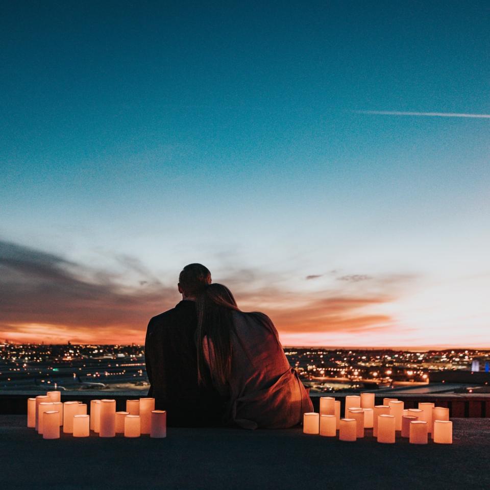 couple sitting on the field facing the city