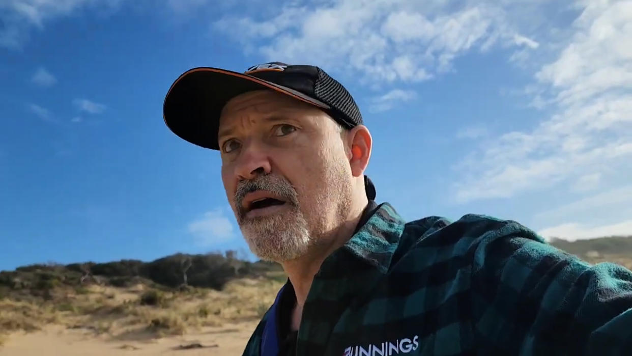 Fisherman Steve Hompot looking to camera shocked. He's on 90 Mile Beach and wearing a Bunnings shirt and a cap. He has a goatee.