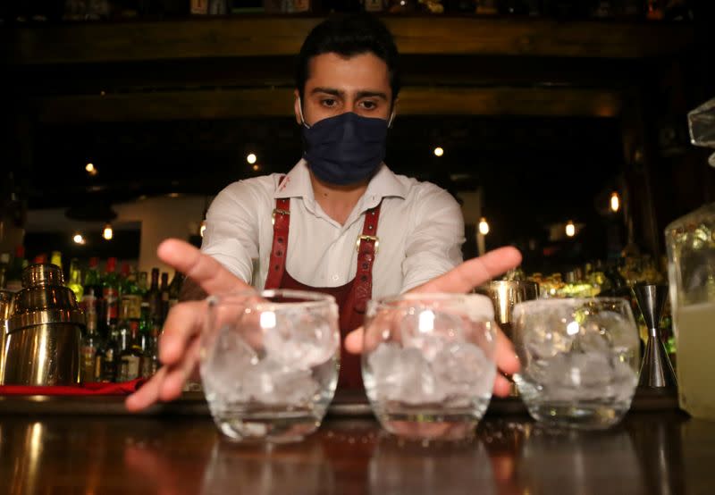 A bartender wearing a protective mask serves drinks at a pub in Beirut