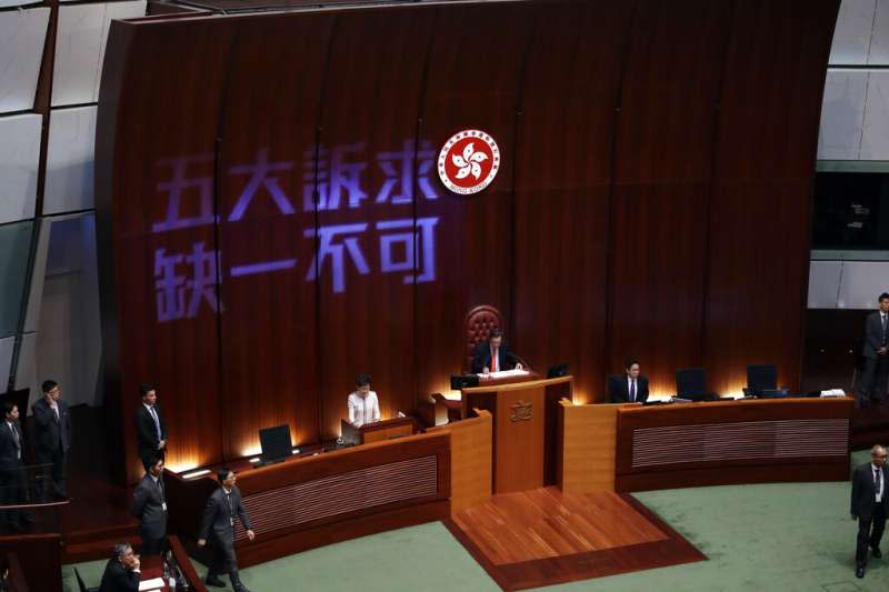 香港特首林鄭月娥16日到立法會進行施政報告，但泛民派議員不斷抗議干擾，還在牆上打出「五大訴求、缺一不可」。（美聯社）