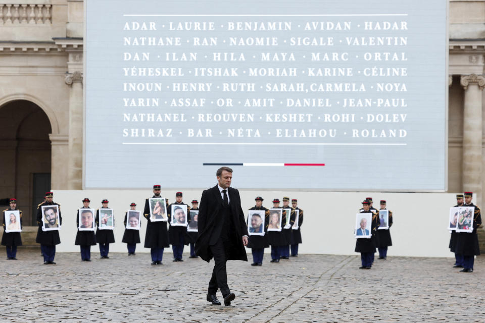 French President Emmanuel Macron walks past French Republican Guards who hold portraits of the French victims of the Oct.7 2023 Hamas' attack, during a ceremony at the Invalides monument, Wednesday, Feb.7, 2024. France is paying tribute to French victims of Hamas' Oct. 7 attack, in a national ceremony led by President Emmanuel Macron four months after the deadly assault in Israel that killed some 1,200 people, mostly civilians, and saw around 250 abducted.(Gonzalo Fuentes/Pool via AP)