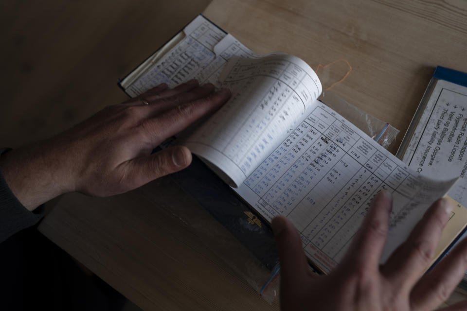 Garrett Fisher, an American aviator and adventurer, opens his log book at his home in Voss, Norway, on Aug. 5, 2022. Fisher, who has flown over 2,000 hours in his life, is on a mission to photograph all the remaining glaciers that are not in the polar regions before they disappear. (AP Photo/Bram Janssen)