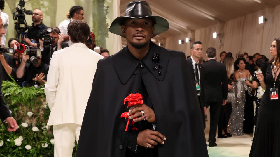Usher's look was a melancholic take on florals, as he entered holding a singular bleeding rose. - John Shearer/WireImage/Getty Images
