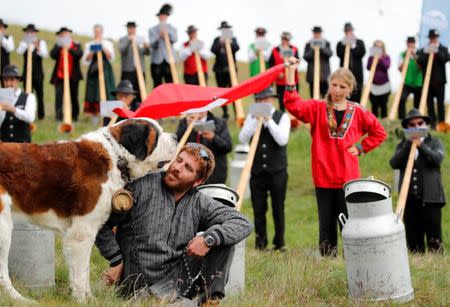 A man with a dog are seen as alphorn blowers perform an ensemble piece on the last day of the Alphorn International Festival on the alp of Tracouet in Nendaz, southern Switzerland, July 22, 2018. REUTERS/Denis Balibouse