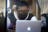 Surrounded by a plastic barrier to prevent the spread of the coronavirus, senior Jose Solano-Hernandez studies with classmates on the first day of in-person learning at Wyandotte High School in Kansas City, Kan., Wednesday, March 30, 2021. Solano-Hernandez, feared he might not graduate after a year of disrupted learning left him missing assignments in most of his classes as he struggled to learn virtually. The school, like other schools nationwide, has made extra efforts to keep kids at risk of dropping out engaged as classes went virtual due to the pandemic. (AP Photo/Charlie Riedel)