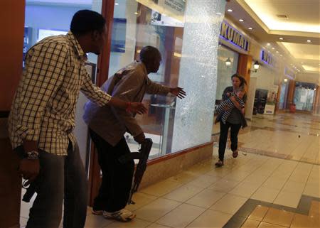 Armed police guide a woman carrying a child to safety as they hunt gunmen who went on a shooting spree at Westgate shopping centre in Nairobi, September 21, 2013. REUTERS/Goran Tomasevic