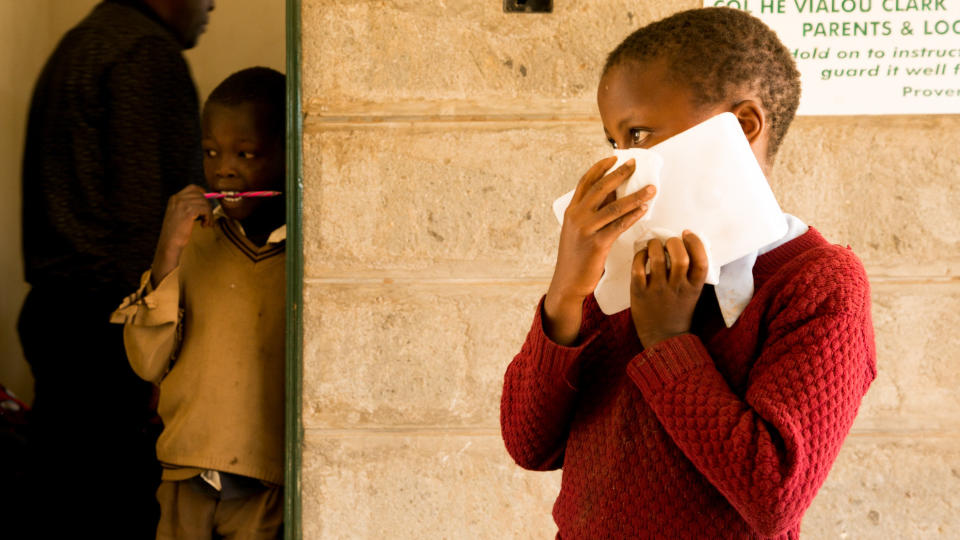 A young schoolgirl holds an ice block to her face to numb areas that will be injected with the painful treatment for cutaneous leishmaniasis at a mobile clinic in rural Kenya. (Photo: Zoe Flood)