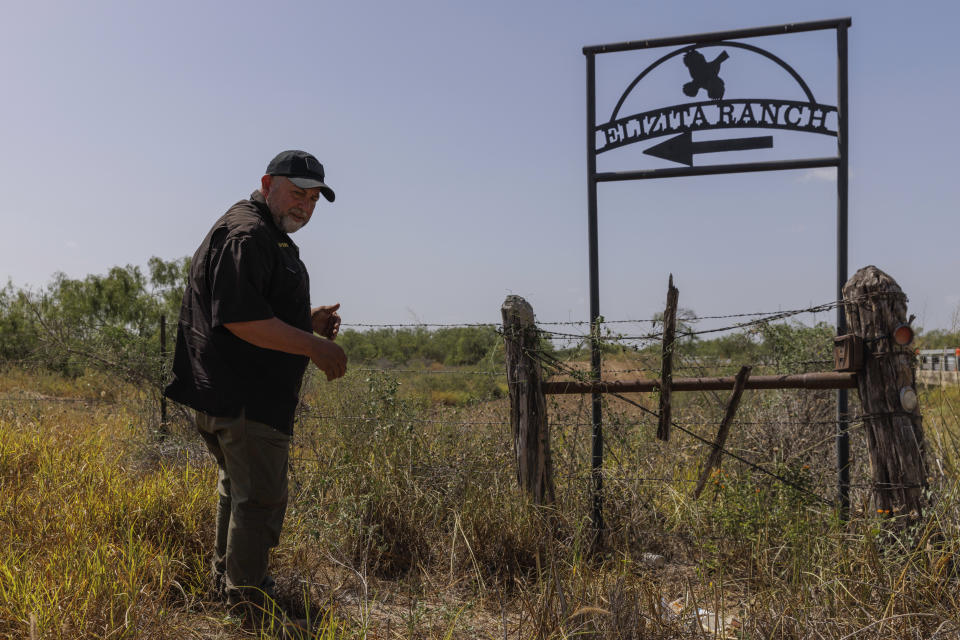 Jim Hogg County Sheriff's Investigator Ruben Garza investigates the location of a missing water station for immigrants containing sealed jugs of fresh water along a fence line near a roadway in rural Jim Hogg County, Texas, Tuesday, July 25, 2023. The South Texas Human Rights Center maintains over 100 blue barrels consistently stocked with water across rural South Texas to serve as a life-saving measure for immigrants who have crossed into the United States to travel north in the sweltering heat. (AP Photo/Michael Gonzalez)