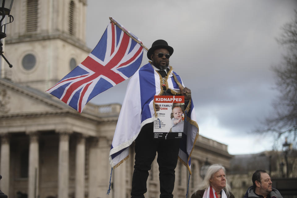 A man holds a Union flag and a poster of kidnapped Israeli baby Kfir Bibas, during a rally supporting Israel, in Trafalgar Square, London, Sunday, Jan. 14, 2024. (Jeff Moore/PA via AP)