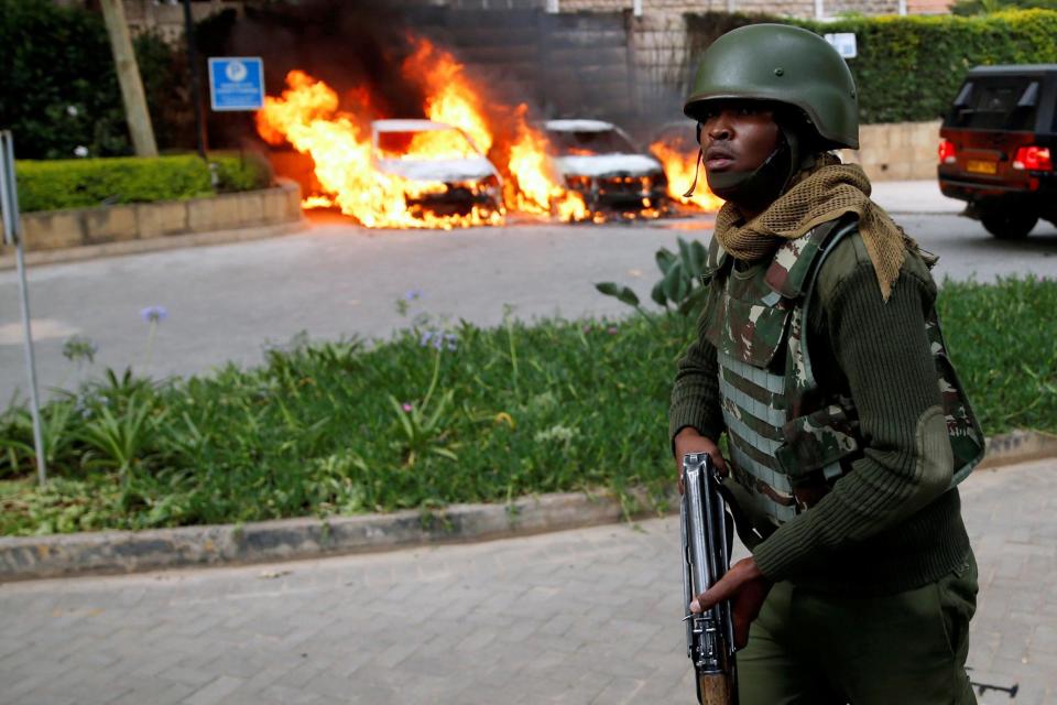 A policeman runs past burning cars at the scene (REUTERS)