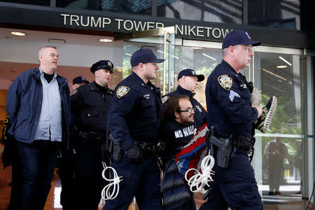 New York City Police officers (NYPD) carry and escorts protestors after making arrests for demonstrating in Trump Tower in New York City, U.S., April 13, 2017. REUTERS/Brendan McDermid