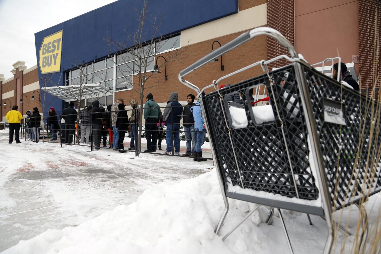 A shopping cart rests in a snowbank as shoppers wait for Best Buy to open.