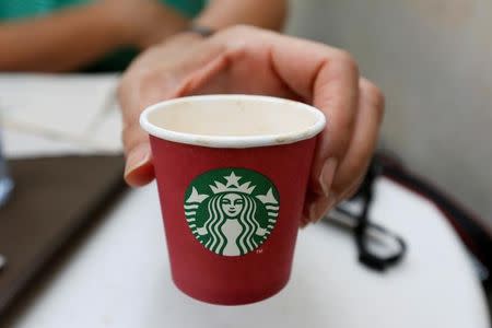 A woman displays a red Starbucks cup at a Starbucks cafe in Beirut, Lebanon November 20, 2016. REUTERS/Jamal Saidi