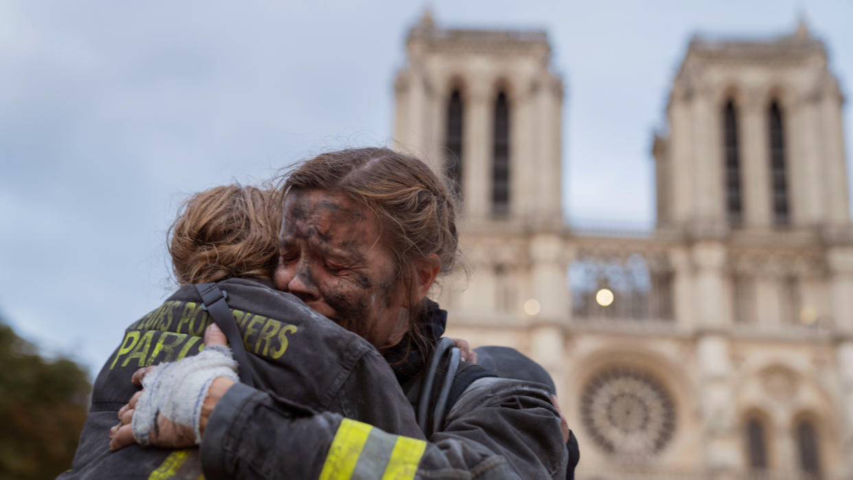  Two firefighters hug in front of Notre-Dame cathedral in the Netflix series 