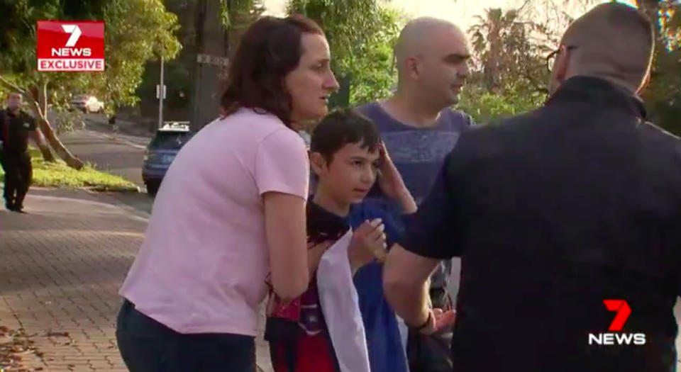 A woman comforts the boy and his father as they wait for emergency services to arrive. Source: 7 News