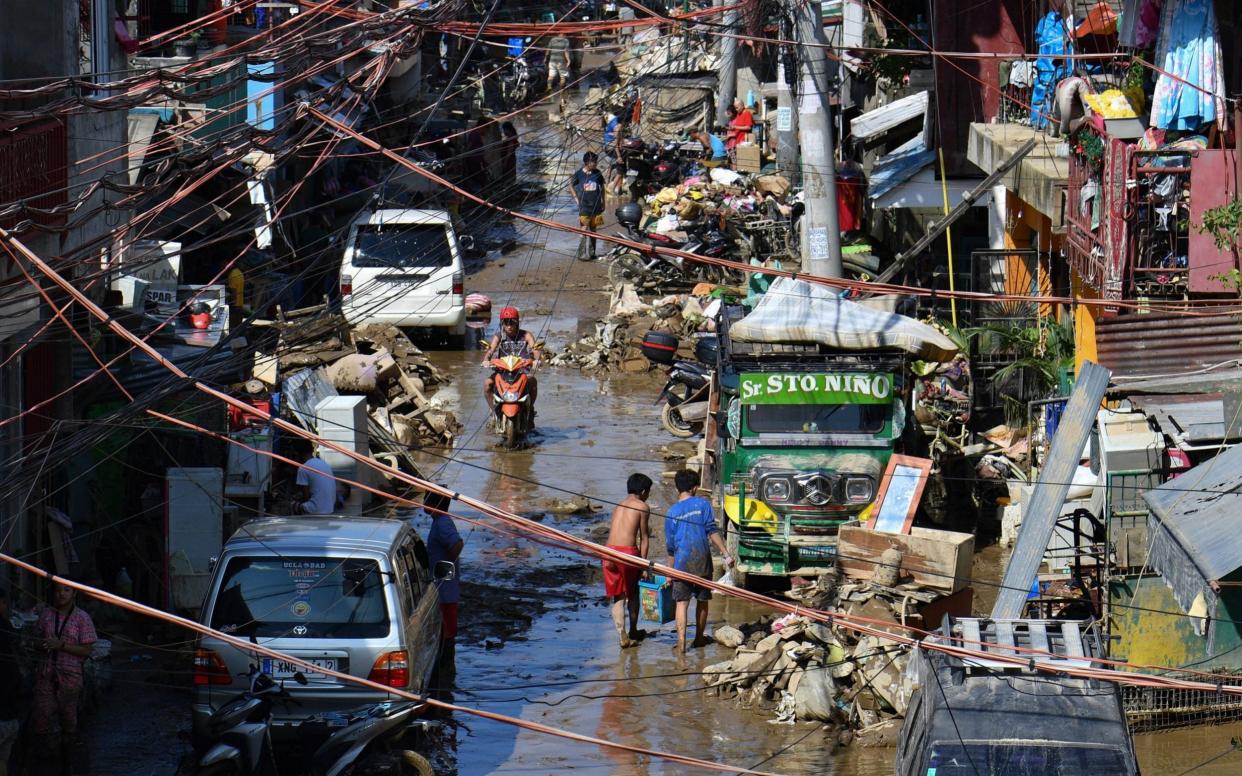 Residents remove mud and debris in front of their flood-damaged houses in Marikina City, suburban Manila a day after Typhoon Vamco hit the capital area  - AFP