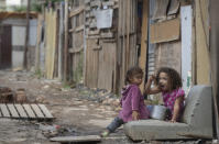 A child eats from a pot as she eyes the camera in the Penha Brasil favela where families have started relocating during the coronavirus pandemic in Sao Paulo, Brazil, Saturday, May 15, 2021. Over 200 families live in the Penha Brasil community, one of the new slums that are sprouting up around Brazil's largest city, inhabited mostly by newly unemployed workers who lost their jobs and homes as a result of the pandemic. (AP Photo/Andre Penner)