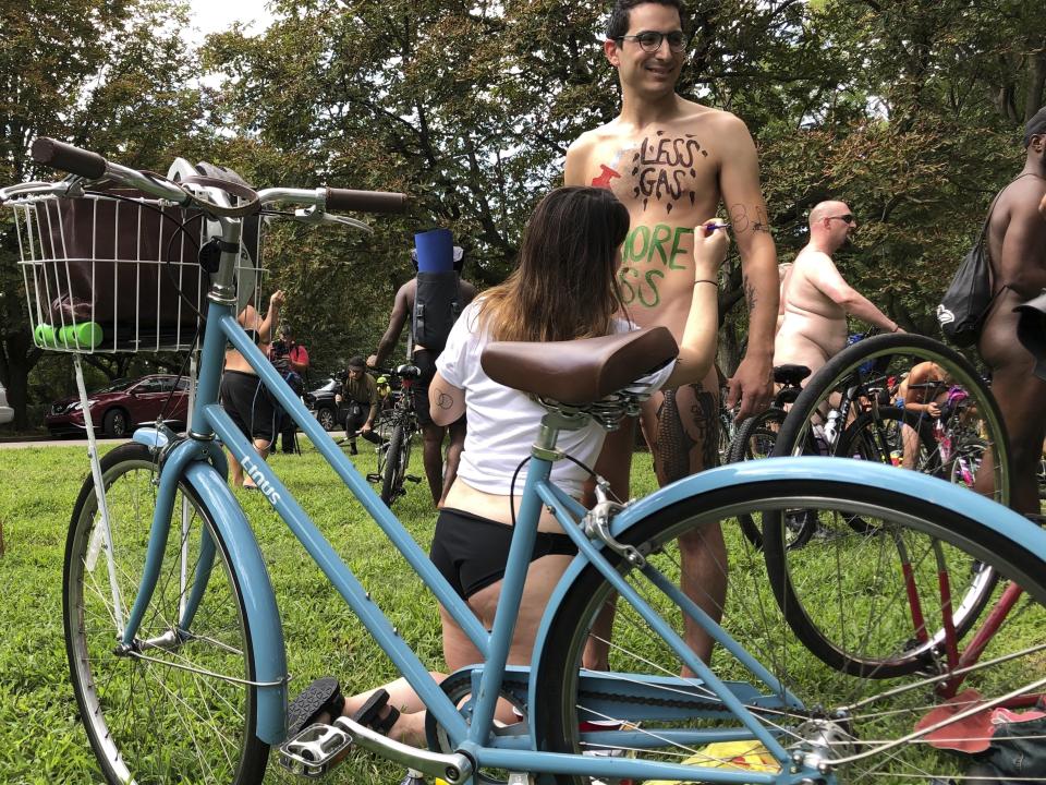 Nude bicyclist Oren Roth-Eisenberg has a message opposing fossil fuel consumption painted on his torso by his wife before the start of the Philly Naked Bike Ride in Philadelphia on Saturday, Aug. 24, 2019. (AP Photo/Dino Hazell)