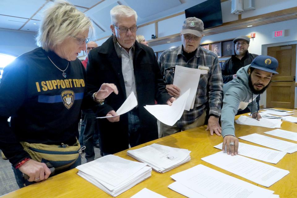 Elizabeth Dorick (left), married to Retired Toms River Police Capt. Michael Dorick, and retired Toms River Police Capt. Jeff Kettig (second from left) pick up copies of the Toms River Council meeting agenda Wednesday, February 14, 2024, shortly before they considered an ordinance which cuts two captains jobs and one patrol officer. Mayor Dan Rodrick said he has already eliminated the need for the council to vote on the ordinance by already making the changes in the department.
(Credit: Thomas P. Costello)