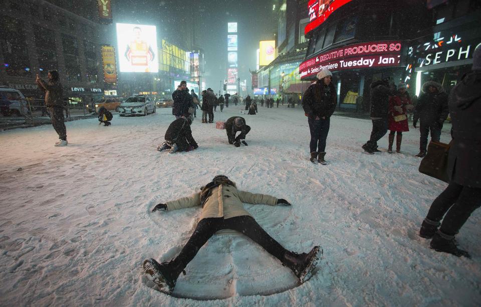 A woman makes a snow angel in the middle of Times Square in New York