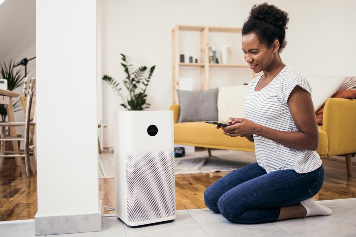 African American woman adjusting a home air cleaner using a smart system