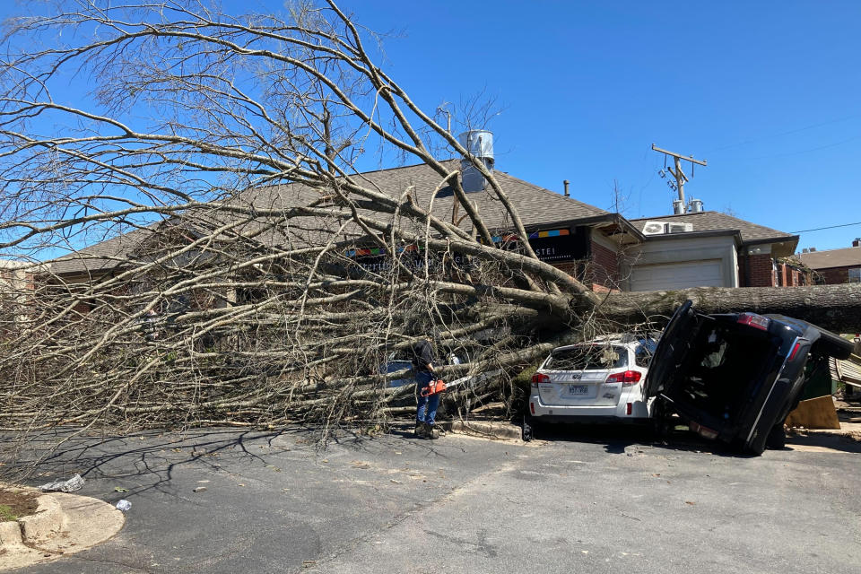 A tree tops two vehicles destroyed by Friday's tornado in Little Rock, Ark., Saturday, April 1, 2023. Unrelenting tornadoes that tore through parts of the South and Midwest that shredded homes and shopping centers. (AP Photo/Andrew DeMillo)