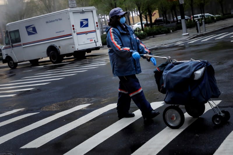 FILE PHOTO: A United States Postal Service (USPS) worker works in the rain in Manhattan during outbreak of coronavirus disease (COVID-19) in New York