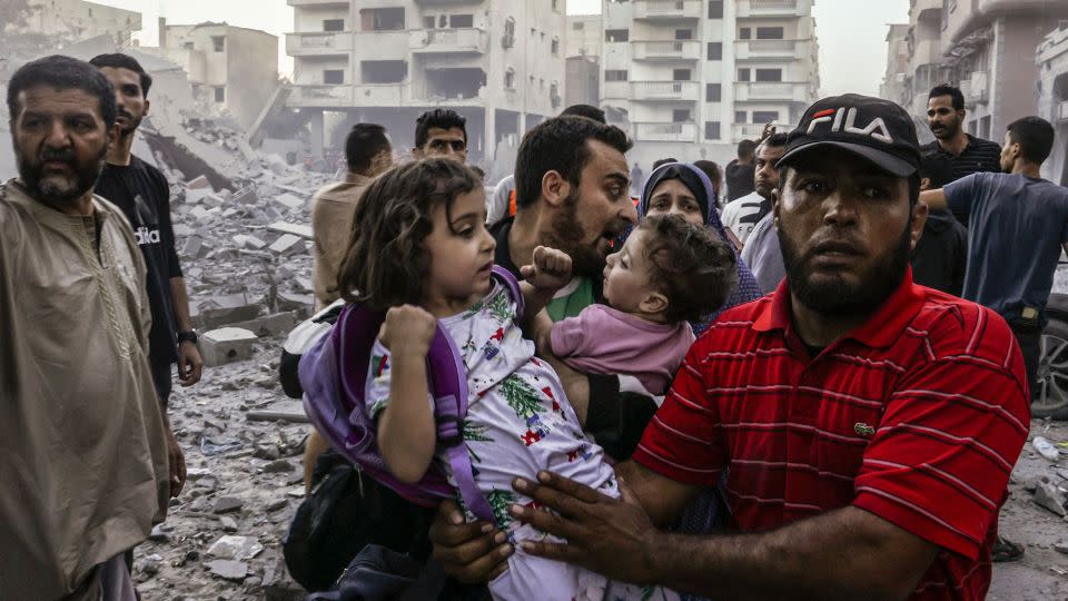 People carry children as they flee, following an Israeli strike on Rafah in the southern Gaza Strip on October 15. - Mohammed Abed/AFP/Getty Images