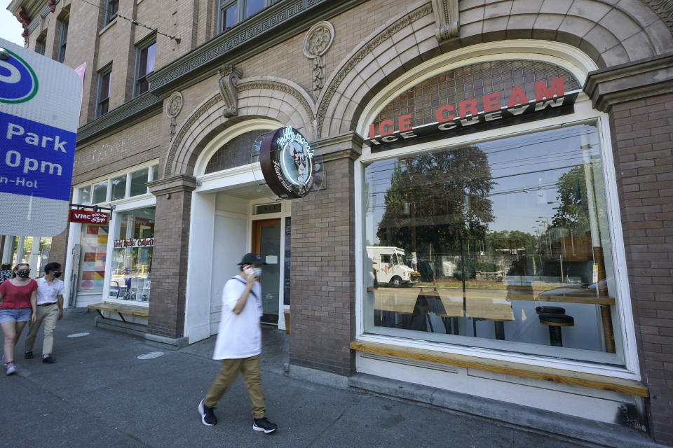 A person walks past a Molly Moon's Ice Cream store in Seattle's Capitol Hill neighborhood, Monday, June 28, 2021, in Seattle. The store was closed Monday due to excessive heat as Seattle and other cities in the Pacific Northwest endured the hottest day of an unprecedented and dangerous heat wave on Monday, with temperatures obliterating records that had been set just the day before on Sunday. (AP Photo/Ted S. Warren)