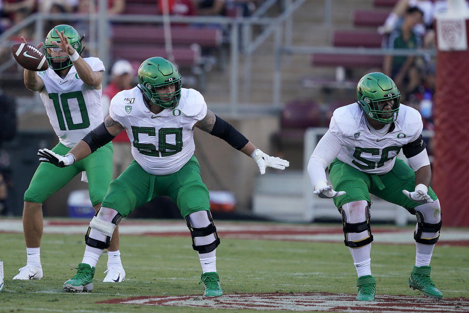 File-This Sept. 21, 2019, file photo shows Oregon offensive linemen Shane Lemieux (68) and Penei Sewell (58) blocks for quarterback Justin Herbert (10) against Stanford during the first half of an NCAA college football game in Stanford, Calif. Caleb Farley of Virginia Tech was the first top prospect to make the decision that has added a whole new layer of uncertainty to the annual crapshoot that is the NFL draft. Farley had plenty of players follow his lead, including several others set to be high draft picks next week like LSU receiver Chase, Oregon tackle Sewell, Northwestern tackle Rashawn Slater and Penn State linebacker Micah Parsons.(AP Photo/Tony Avelar, File)