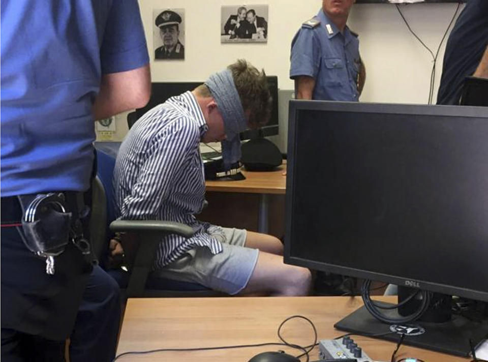 In this photo obtained from Italian Carabinieri, Gabriel Christian Natale-Hjorth sits blindfolded in a police station in Rome on Friday July 26, 2019. Natale-Hjorth, a suspect in the slaying of police officer Deputy Brigadier Mario Cerciello Rega, was blindfolded before he was interrogated in Rome, an Italian police commander said Sunday July 28 after the emergence of a photo showing the young tourist restrained with handcuffs and with his head bowed. Natale-Hjorth and another suspect from California, 19-year-old Finnegan Lee Elder remain jailed, while the murdered police officer Mario Cerciello Rega is to be buried in southern Italy on Monday. (Italian Carabinieri via AP)