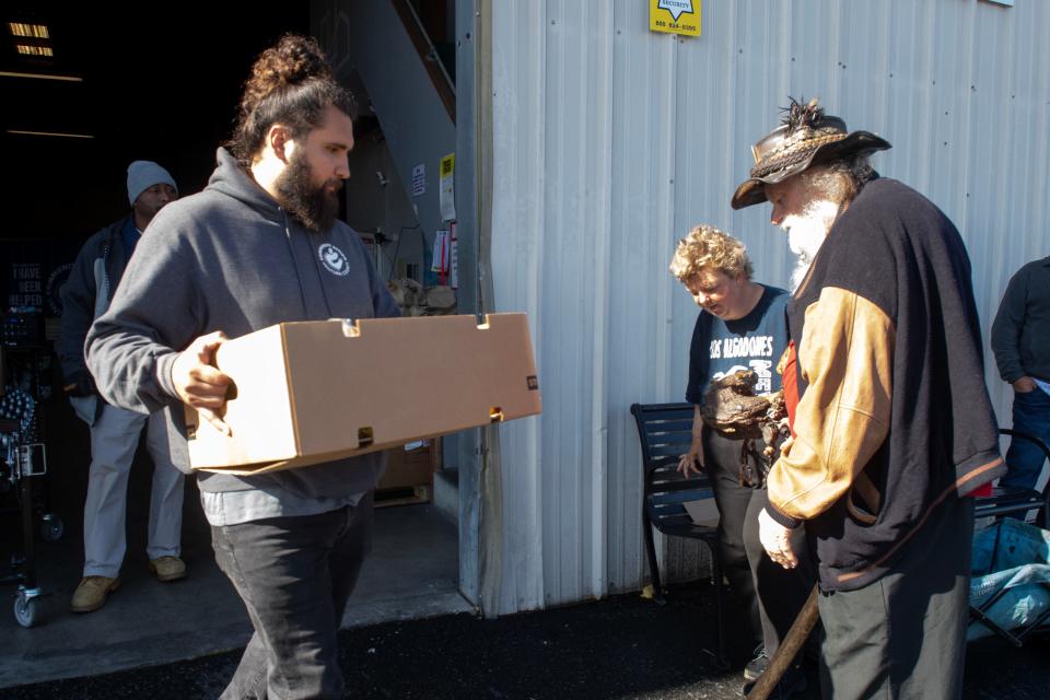 Russell Wilson, left, of Community Action of Ventura County, carries a box of groceries for Heather Padgett and William Matlock during a food pantry event at the nonprofit's Oxnard facility on May 4.