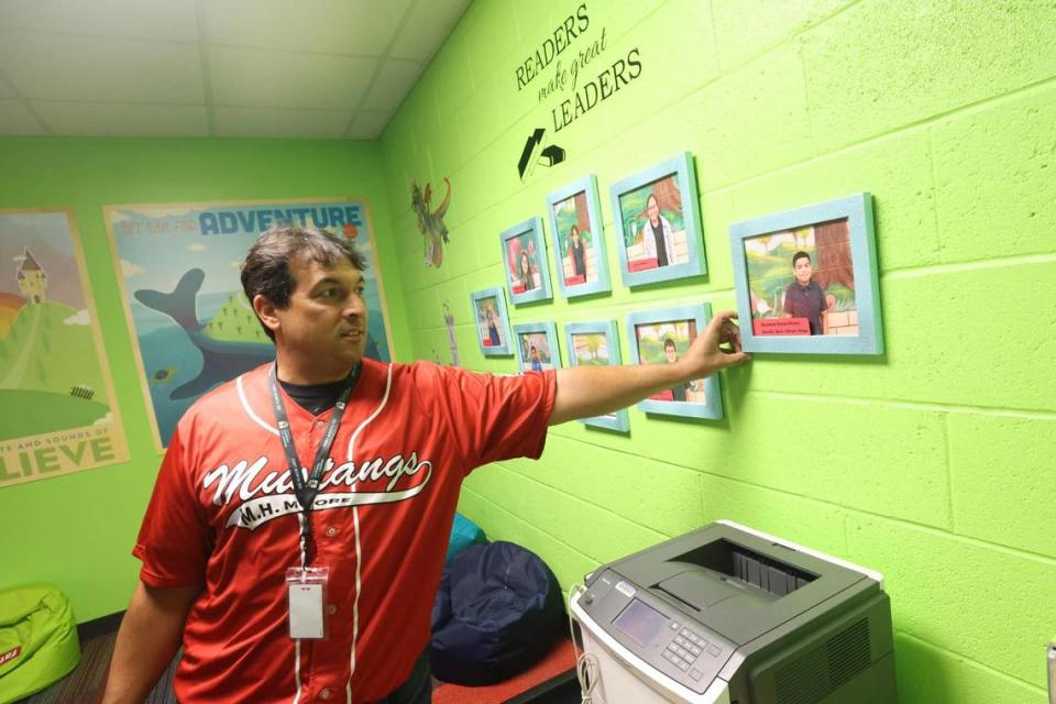 Ricardo Alvarez, the principal at M.H. Moore Elementary School, talks about the best reading students, whose photos are framed on the wall in the school’s library, in Fort Worth on July 28. The district is in the second year of implementing a new reading curriculum.