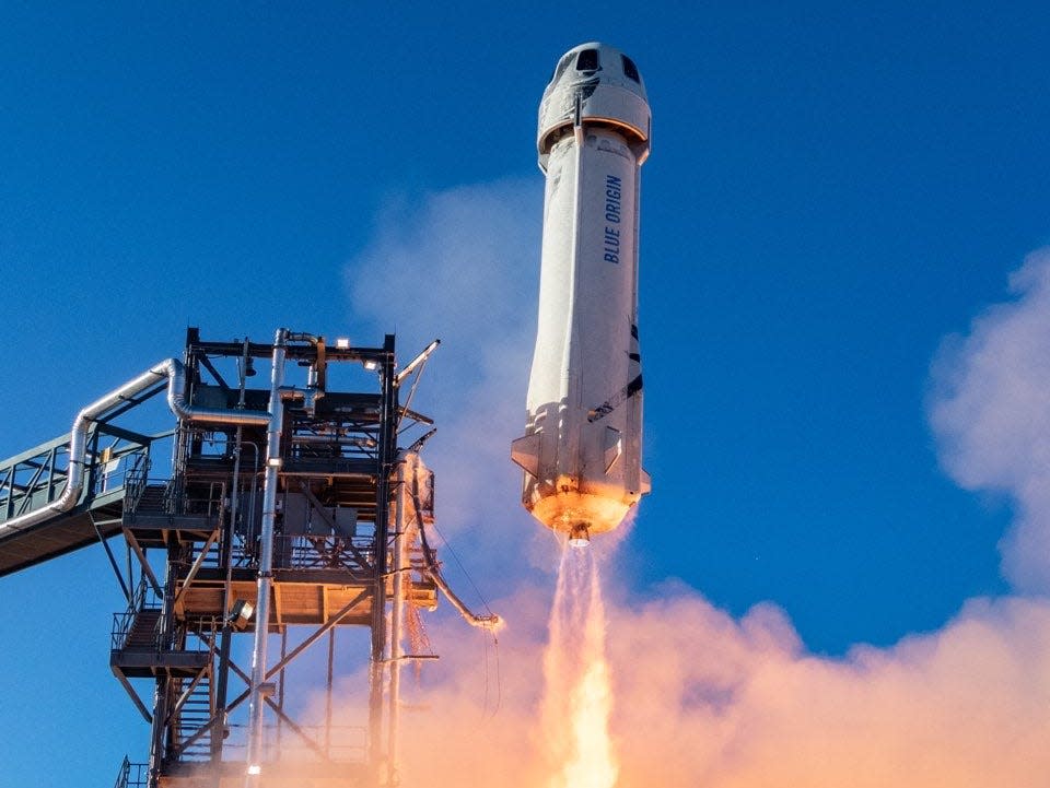 A Blue Origin rocket launching into a blue sky.