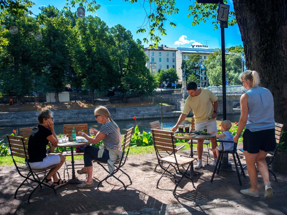 A couple and a small family sit outside at a café in Turku, Finland.