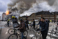 People ride bicycles as smoke rises from the Old Stock Exchange in Copenhagen, Denmark, Tuesday, April 16, 2024. A fire raged through one of Copenhagen’s oldest buildings on Tuesday, causing the collapse of the iconic spire of the 17th-century Old Stock Exchange as passersby rushed to help emergency services save priceless paintings and other valuables. (Emil Nicolai Helms/Ritzau Scanpix via AP)