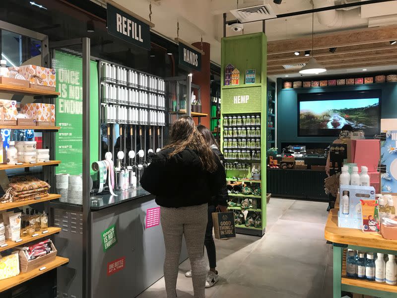 FILE PHOTO: Customers look at a station for refilling shower gel at a Body Shop store on Bond Street in London