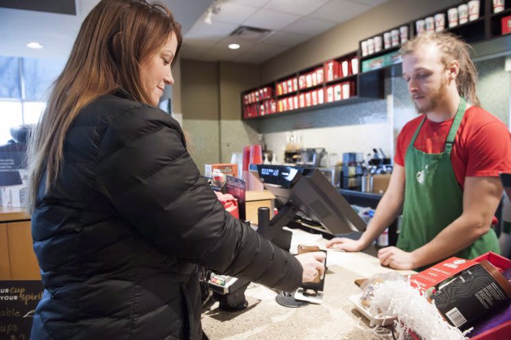 Maureen Turner uses her phone to pay for her coffee at a Starbucks in Mississauga, Ont. on Saturday, Dec. 19, 2015. (THE CANADIAN PRESS/Hannah Yoon)