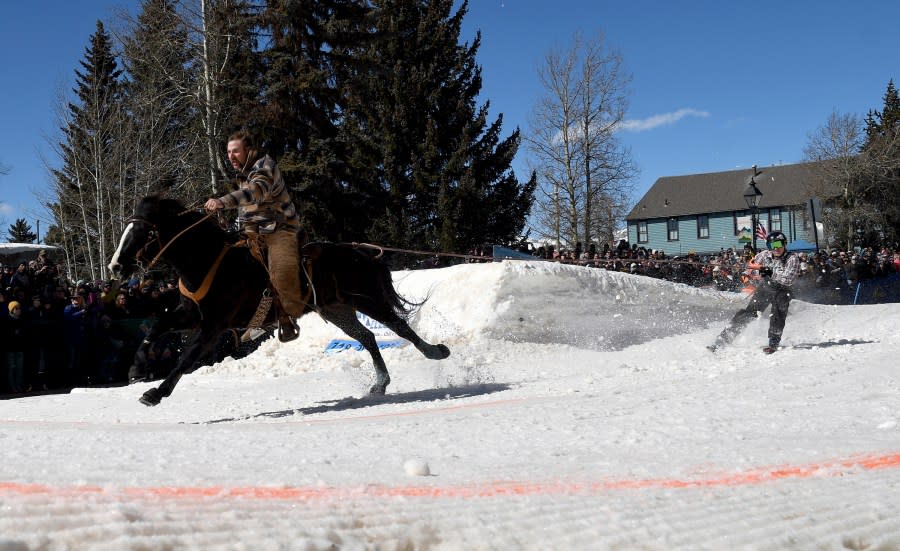 A skijoring team competes in Leadville, Colo., on Saturday, March 2, 2024. Skijoring draws its name from the Norwegian word skikjoring, meaning “ski driving.” It started as a practical mode of transportation in Scandinavia and became popular in the Alps around 1900. Today’s sport features horses at full gallop towing skiers by rope over jumps and around obstacles as they try to lance suspended hoops with a baton, typically a ski pole that’s cut in half. (AP Photo/Thomas Peipert)