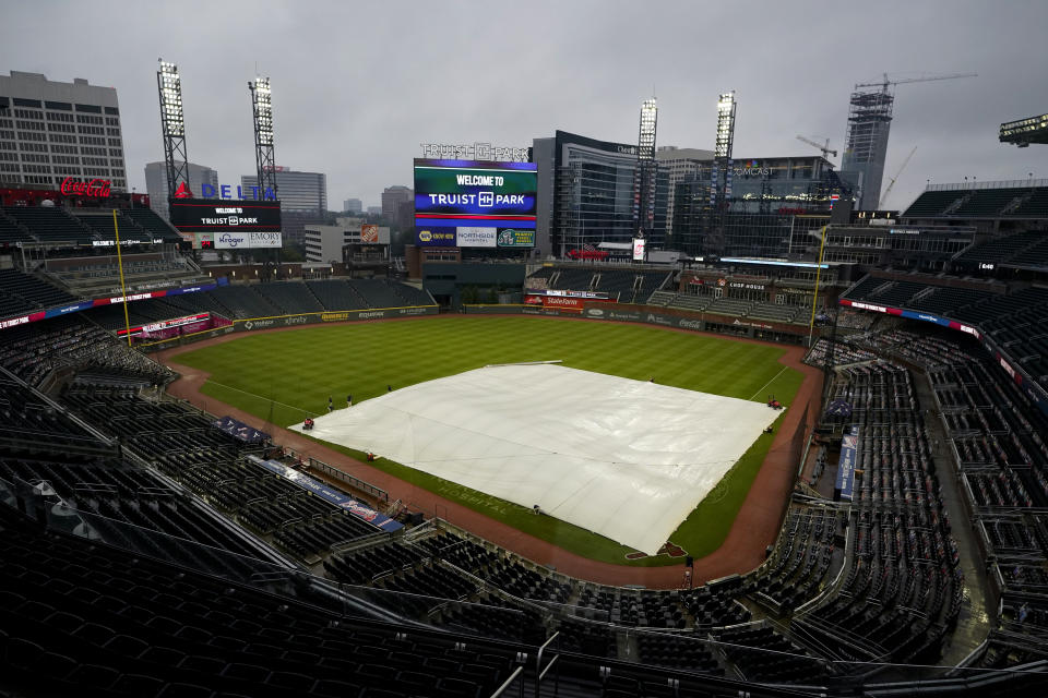 A tarp covers the infield at Truist Park during a rain shower before the scheduled start of a baseball game between the Atlanta Braves and the Miami Marlins on Thursday, Sept. 24, 2020, in Atlanta. (AP Photo/John Bazemore)