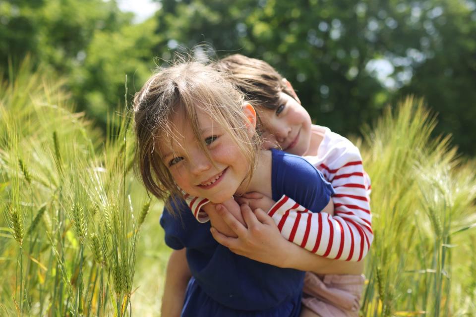 a girl carrying her little brother in a wheat field