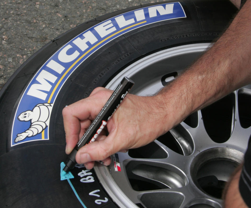 FILE - This June 30, 2005 file photo shows a Michelin team technician writing on a Michelin tire in the paddock at Magny Cours circuit, central France, ahead the French Formula One Grand Prix. Michelin SCA's recent production cuts, made to adjust to sharply falling demand amid the global economic crisis, will cost euro 150 million ($209 million) in the fourth quarter, the French tire maker said Monday Dec.22, 2008. (AP Photo/Michel Spingler)