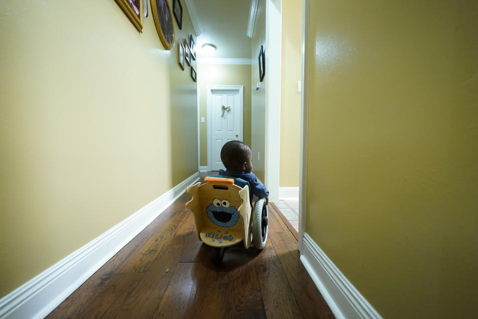 Elijah Jack, 1, wheels himself through his home in his mobility chair, which was built as a donation by Tulane University students, at his home in New Roads, La., Thursday, Nov. 30, 2023. Tulane science and engineering students are making the second batch of mobility chairs for toddlers, that will eventually go to pediatric patients at Children's Hospital. Wheelchairs are expensive, and insurance won't cover the cost for children unless the child proves they can operate it independently. (AP Photo/Gerald Herbert)