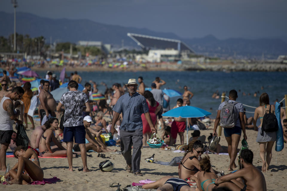 People enjoy the beach in Barcelona, Spain, Saturday, July 18, 2020. Police in Barcelona are closing access to a large area of the city's beaches due to the excess of sunbathers who decided to ignore the urgings of authorities to stay at home amid a resurgence of the coronavirus. (AP Photo/Emilio Morenatti)