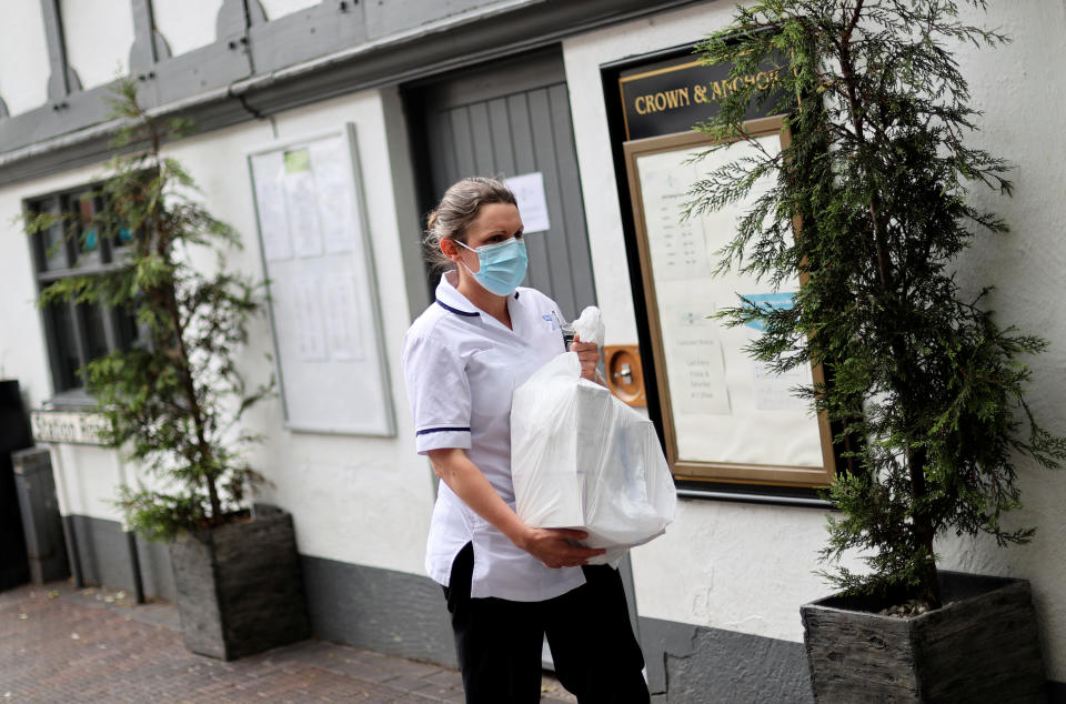 A woman wearing a face mask walks outside the Crown and Anchor pub following a spike in cases of the coronavirus disease (COVID-19) to visitors of the pub in Stone, Britain, July 29, 2020. REUTERS/Carl Recine