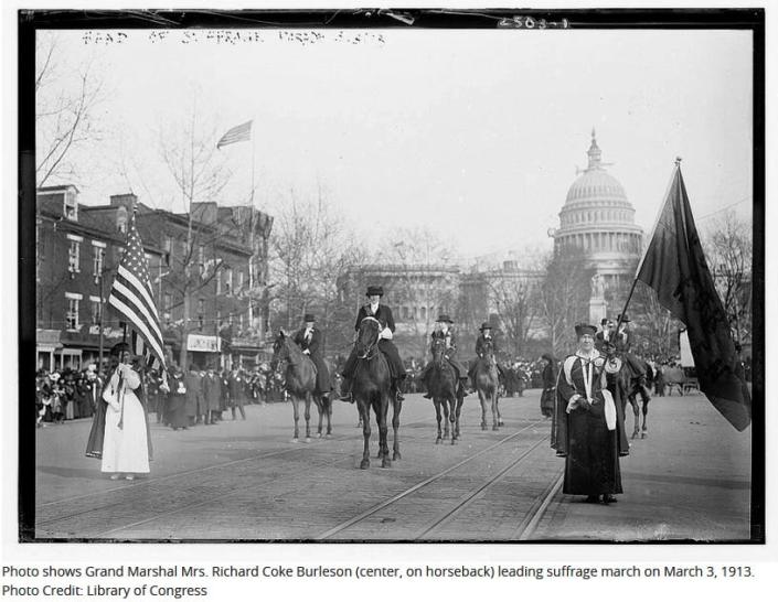 Photo shows Grand Marshal Mrs.  Richard Coke Burleson (center, on horseback) leading the suffrage march on March 3, 1913.